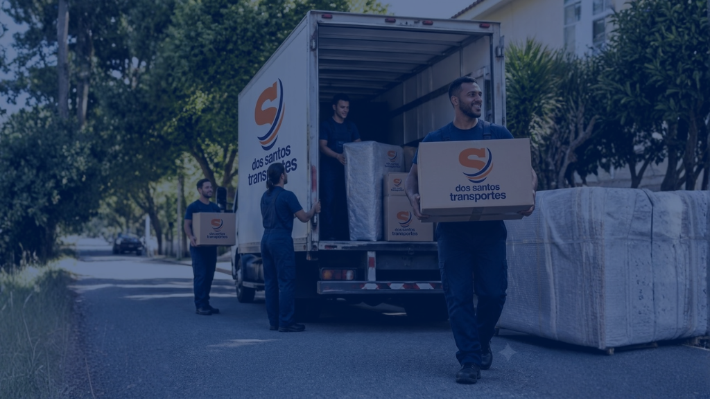 Equipe da Dos Santos Transportes carregando caixas e móveis embalados em um caminhão de mudança em rua residencial